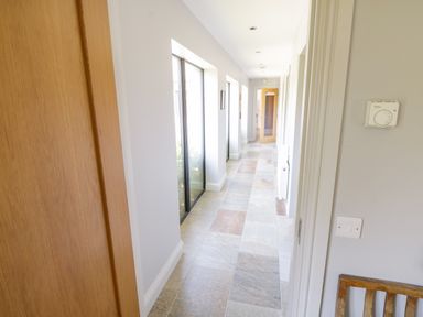 A hallway with tiled floor and windows on one side and doors on the other at The Visiting House in Gorteen near Dunmore County Galway