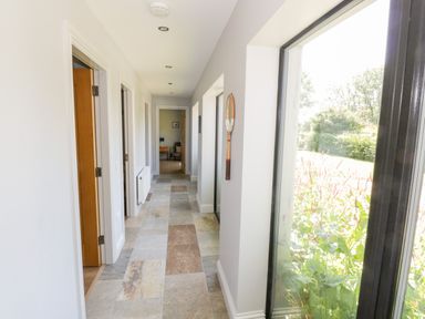 A hallway with tiled floor and white walls with a window showing garden outside at The Visiting House in Gorteen near Dunmore County Galway