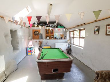 A room with a pool table dartboard window chair and string of colorful flags at The Visiting House in Gorteen near Dunmore County Galway