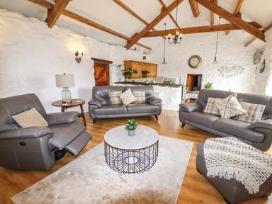 A living room with gray sofas a round coffee table and wooden beams at Y Bwthyn in Ysbyty Ifan