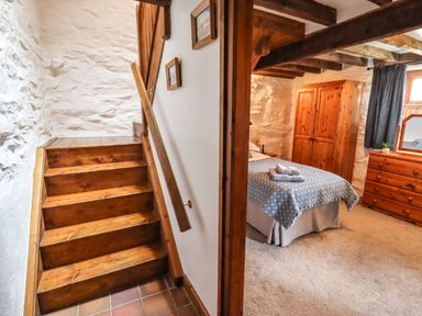 A wooden staircase next to a bedroom with a bed and wooden furniture at Y Bwthyn in Ysbyty Ifan