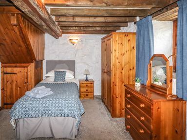 A bedroom with a single bed wooden wardrobe chest of drawers and bedside table at Y Bwthyn in Ysbyty Ifan