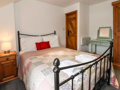 A bedroom with a metal bed frame patchwork quilt bedside table with lamp wooden door dressing table with mirror at The Cottage Kilham near Driffield