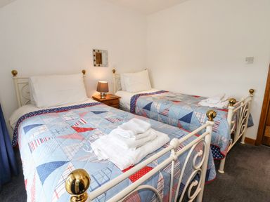 A bedroom with two single beds and a bedside table with a lamp at The Cottage in Kilham near Driffield