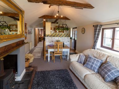 A living room with a sofa and dining table in a cottage at Cwm Derw Cottage in Llanafan Fawr near Builth Wells