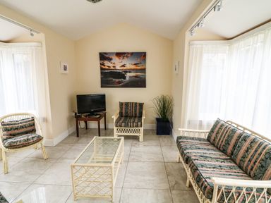 A living room with wicker furniture and a glass coffee table at Sutton Cottage Ballysheen near Rosslare Harbour County Wexford