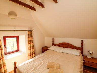 A bedroom with a double bed two nightstands and a window with curtains at Sutton Cottage Ballysheen near Rosslare Harbour County Wexford