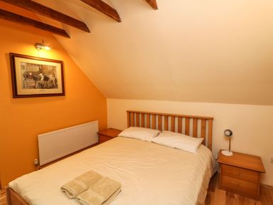 A bedroom with a double bed bedside tables a lamp and artwork on the wall at Sutton Cottage Ballysheen near Rosslare Harbour County Wexford
