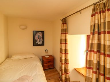 A small bedroom with a single bed bedside table with lamp and closed curtains at Sutton Cottage Ballysheen near Rosslare Harbour County Wexford