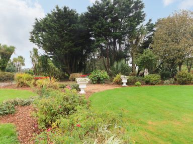 A garden with green grass shrubs and trees at Sutton Cottage Ballysheen near Rosslare Harbour County Wexford
