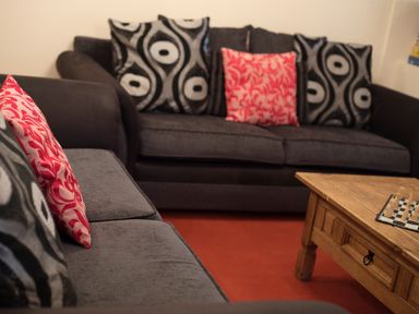 A sitting area with two dark sofas with patterned cushions and a wooden coffee table with a chessboard at Brambles Cottage in Little Malvern near Malvern