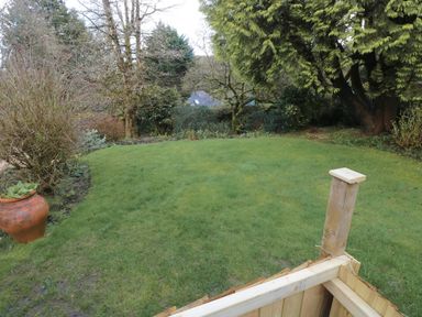 A garden with grass lawn trees shrubs and a large planter pot at The Garden Flat in Saundersfoot