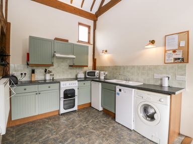 A kitchen with green cabinets white appliances and a tiled floor at Stable End in Luntley near Pembridge