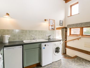 A kitchen area with a sink dishwasher washing machine and kettle at Stable End in Luntley near Pembridge