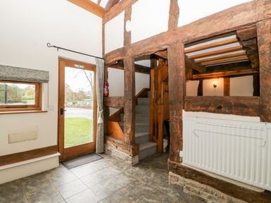 Entry area with wooden framed door and window stone tiled floor staircase and exposed wooden beams at Stable End in Luntley near Pembridge