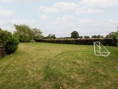 A grassy field with two small soccer goals and trees and hedges surrounding the area at Stable End in Luntley near Pembridge