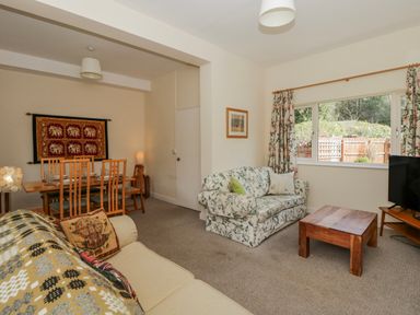 A living room featuring a sofa, dining area and television at Gardener's Cottage in Llanwrthwl near Rhayader