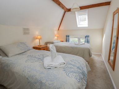 A bedroom with two beds and a mirror at Gardener's Cottage in Llanwrthwl near Rhayader