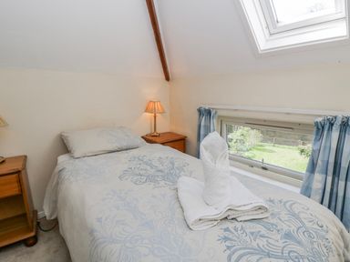 A bedroom with a single bed and bedside lamp at Gardener's Cottage Llanwrthwl near Rhayader