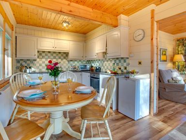 A kitchen and dining area with a round table set for four and a living room with a sofa at Apple Tree Lodge Swarland near Alnwick