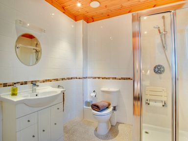 A bathroom with a sink cabinet mirror toilet with folded towels and a shower with a seat at Apple Tree Lodge Swarland near Alnwick