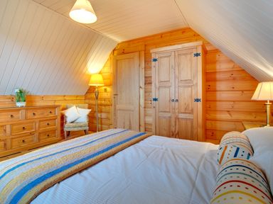 A bedroom with a bed and wooden furniture including a wardrobe and a dresser at Lime Tree Lodge Swarland near Alnwick