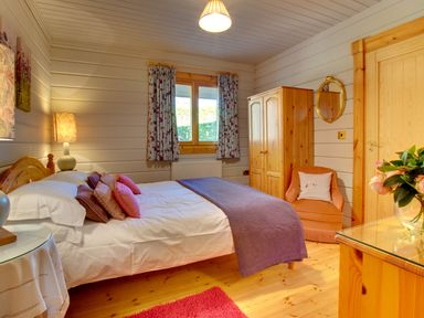A bedroom with a double bed covered with pillows and a blanket at Lime Tree Lodge Swarland near Alnwick