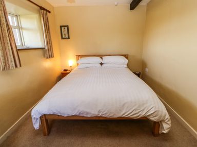 A bedroom with a double bed bedside tables a window and curtains at Cherry Tree Cottage Soulby near Kirkby Stephen