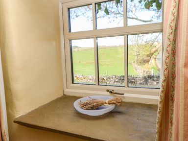 A window with a stone sill and a plate with dried herbs inside Cherry Tree Cottage in Soulby near Kirkby Stephen