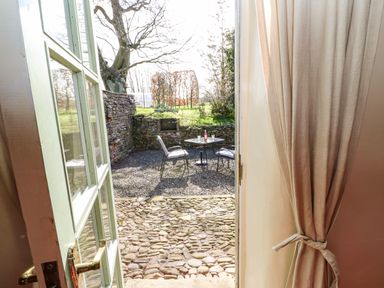 A view through an open door to an outdoor patio with chairs and a table at Cherry Tree Cottage in Soulby near Kirkby Stephen