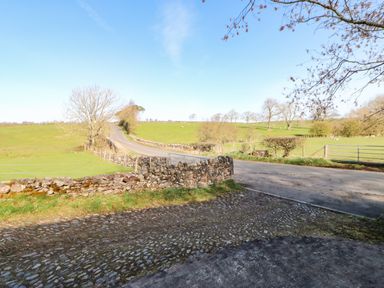A country road with stone walls and green fields on both sides at Cherry Tree Cottage in Soulby near Kirkby Stephen