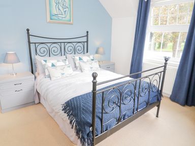 A bedroom with a metal frame bed white bedding blue throw pillows blue curtains and bedside tables with lamps at Mountain View in Conwy