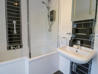 A bathroom with a bathtub shower combination and a wall-mounted sink at Mountain View in Conwy