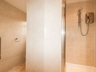 A tiled bathroom with a shower unit and a handheld showerhead at Brocks Barn in Sweetshouse near Lostwithiel