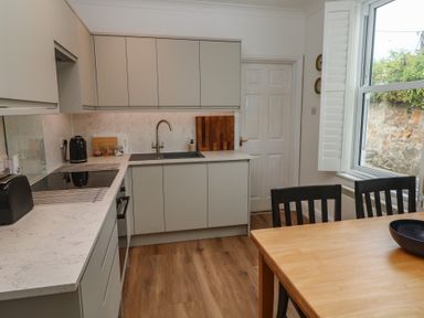 A kitchen with cabinets and a dining table at Apartment 1 Llewellan St Ives