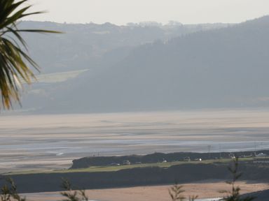 A coastal landscape with sand dunes water and hills in the background at Beach View in Benllech near Red Wharf Bay
