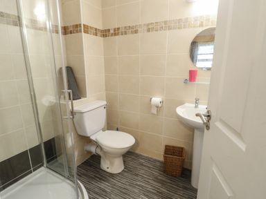 A bathroom with a shower, toilet, and sink at Beach View in Benllech near Red Wharf Bay