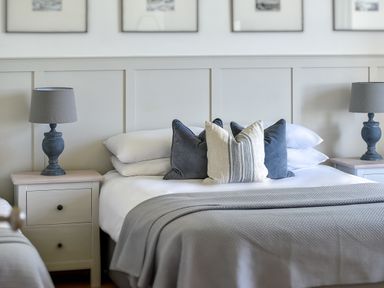 A bedroom with a bed and pillows between two bedside tables with lamps at Ty Carmel in Rhosneigr