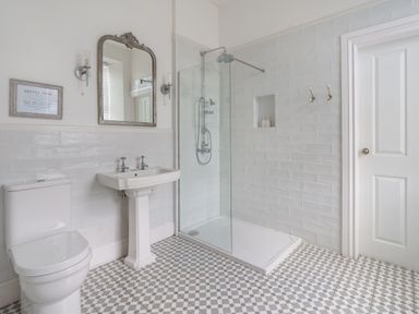 A bathroom with a toilet sink mirror shower and tiled floor at Ty Carmel in Rhosneigr