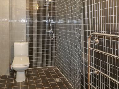 A bathroom with a toilet shower and a towel rack with black and white tiles at Y Beudy in Criccieth