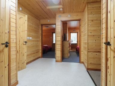 A wooden hallway with multiple doorways leading to bedrooms at Birch Lodge in Rosliston