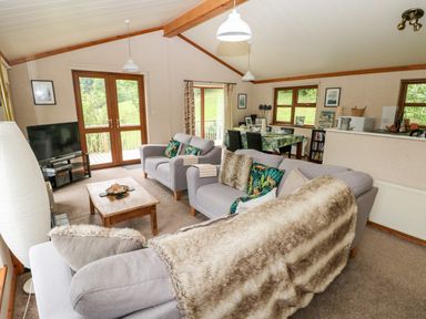 A living room with two sofas a wooden coffee table a television and a dining area at The Beeches in Narberth