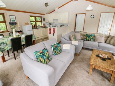 A living room with sofas pillows and a wooden coffee table next to a dining table and an open kitchen at The Beeches in Narberth