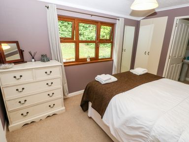 A bedroom with a bed folded towels on a brown throw a white chest of drawers a window and wardrobes at The Beeches in Narberth