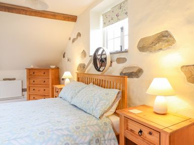 A bedroom with a wooden bed and bedside tables with lamps and a chest of drawers at Ysgybor Yd in Chwilog near Criccieth