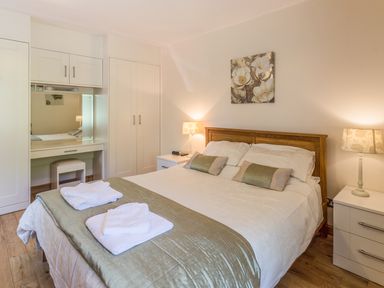 A bedroom with a double bed bedside tables lamps and built in wardrobes at Gardeners Cottage in Belford near Bamburgh