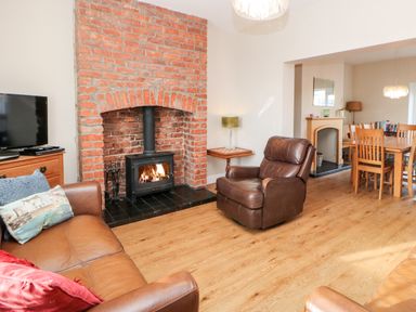 A living room with a brick fireplace leather chairs a wooden dining table and a television at Lightkeeper House in Amble-by-the-Sea