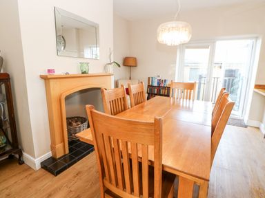 A dining room with a wooden table and chairs a fireplace and a bookshelf at Lightkeeper House in Amble-by-the-Sea
