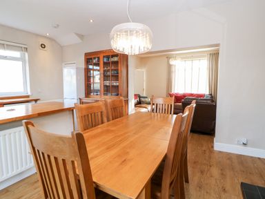 A dining room with a wooden table and chairs next to a kitchen area and a living room at Lightkeeper House in Amble-by-the-Sea