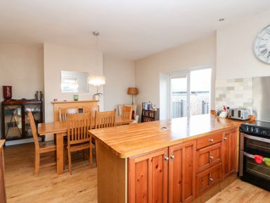 A kitchen and dining area with wooden furniture and a large island at Lightkeeper House in Amble-by-the-Sea